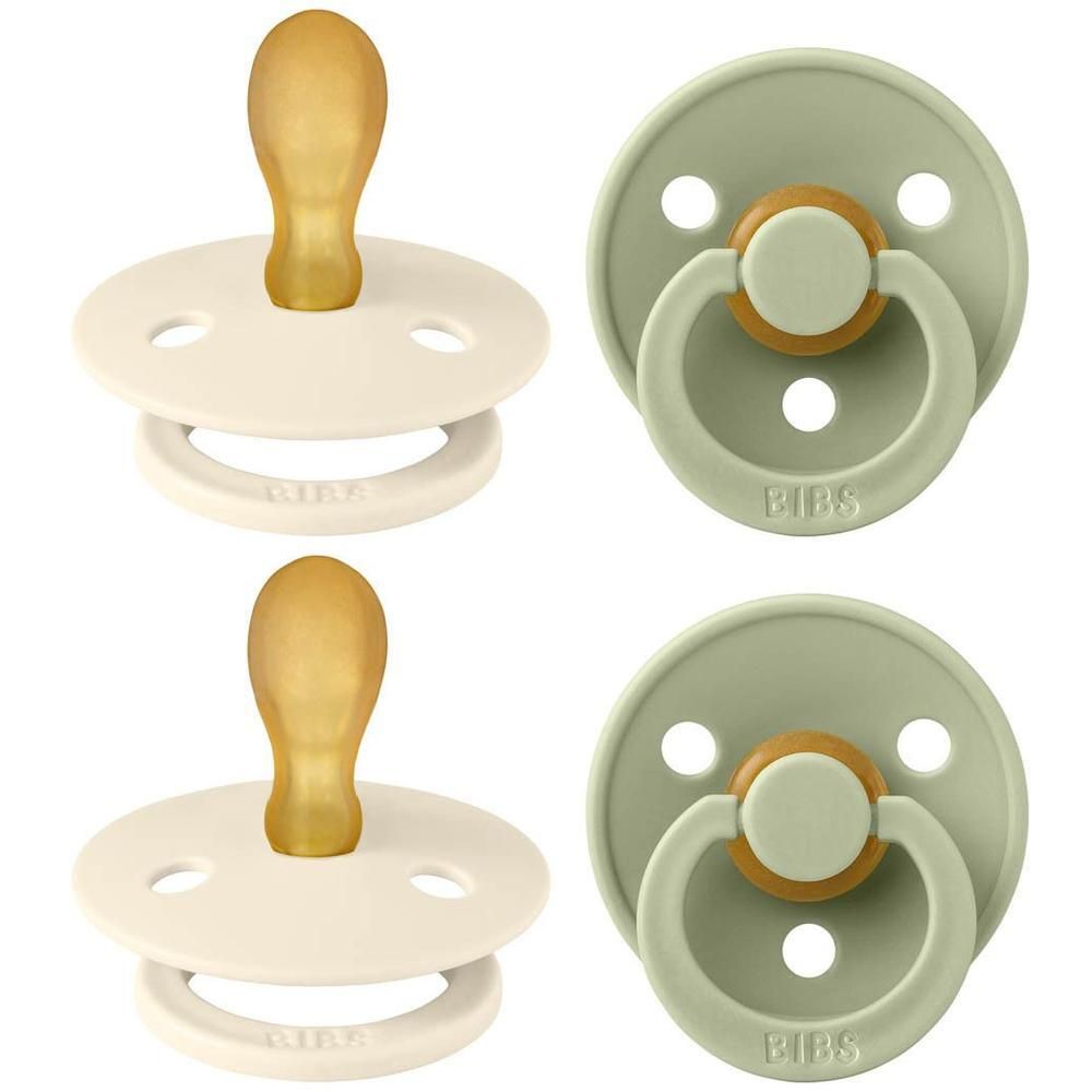 Deux suces BIBS : une couleur crème et une vert sauge, avec tétine et anneau en caoutchouc naturel ambré.
