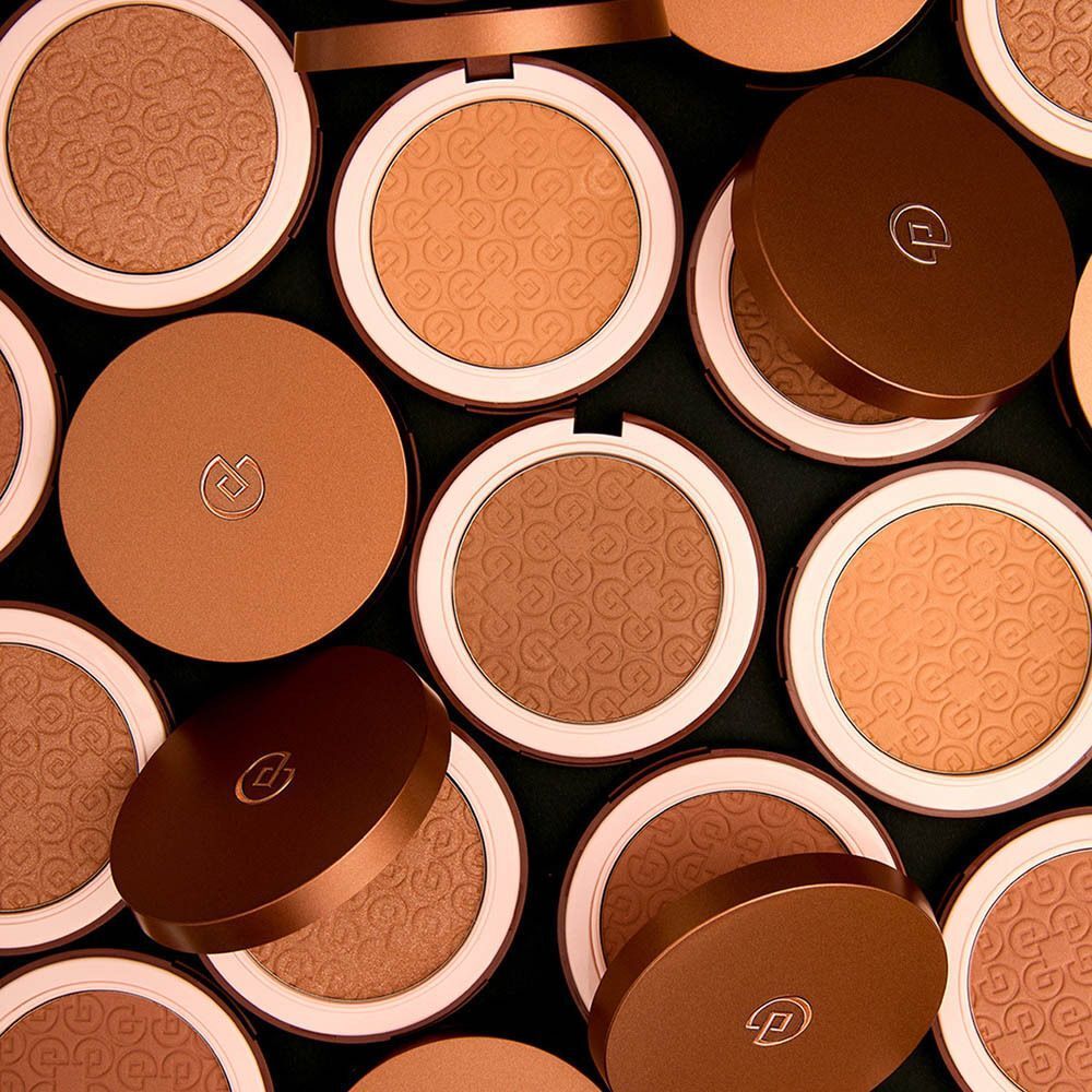 Veel bronzing poeders in ronde doosjes, sommige met open deksels.