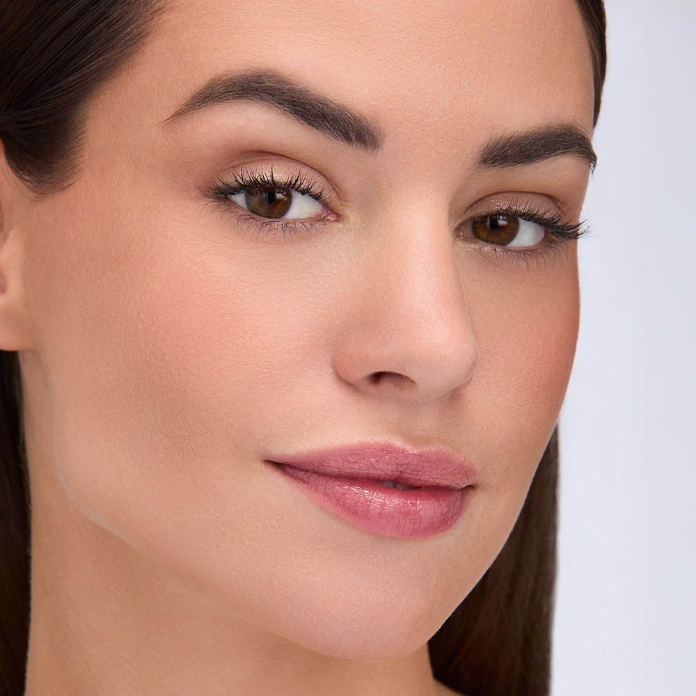 Gros plan d'une femme au teint impeccable et au maquillage subtil.