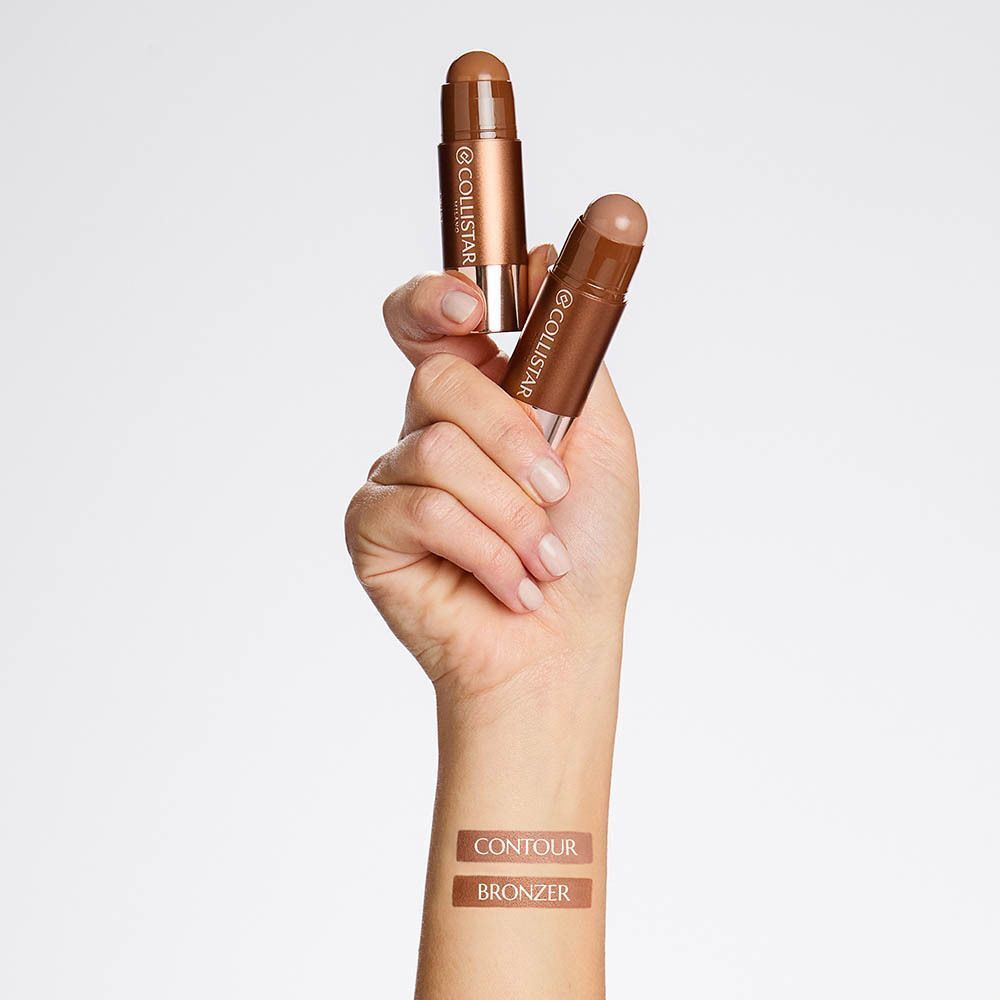 Une main tient deux sticks Collistar Twist Velvet Bronzer, avec des échantillons de couleur sur l'avant-bras.
