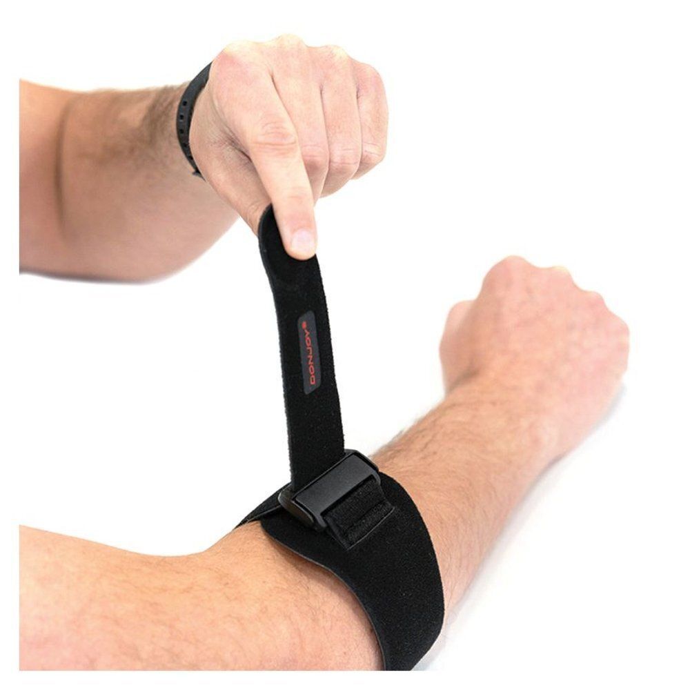 Une main ajuste une genouillère noire avec fermeture velcro.