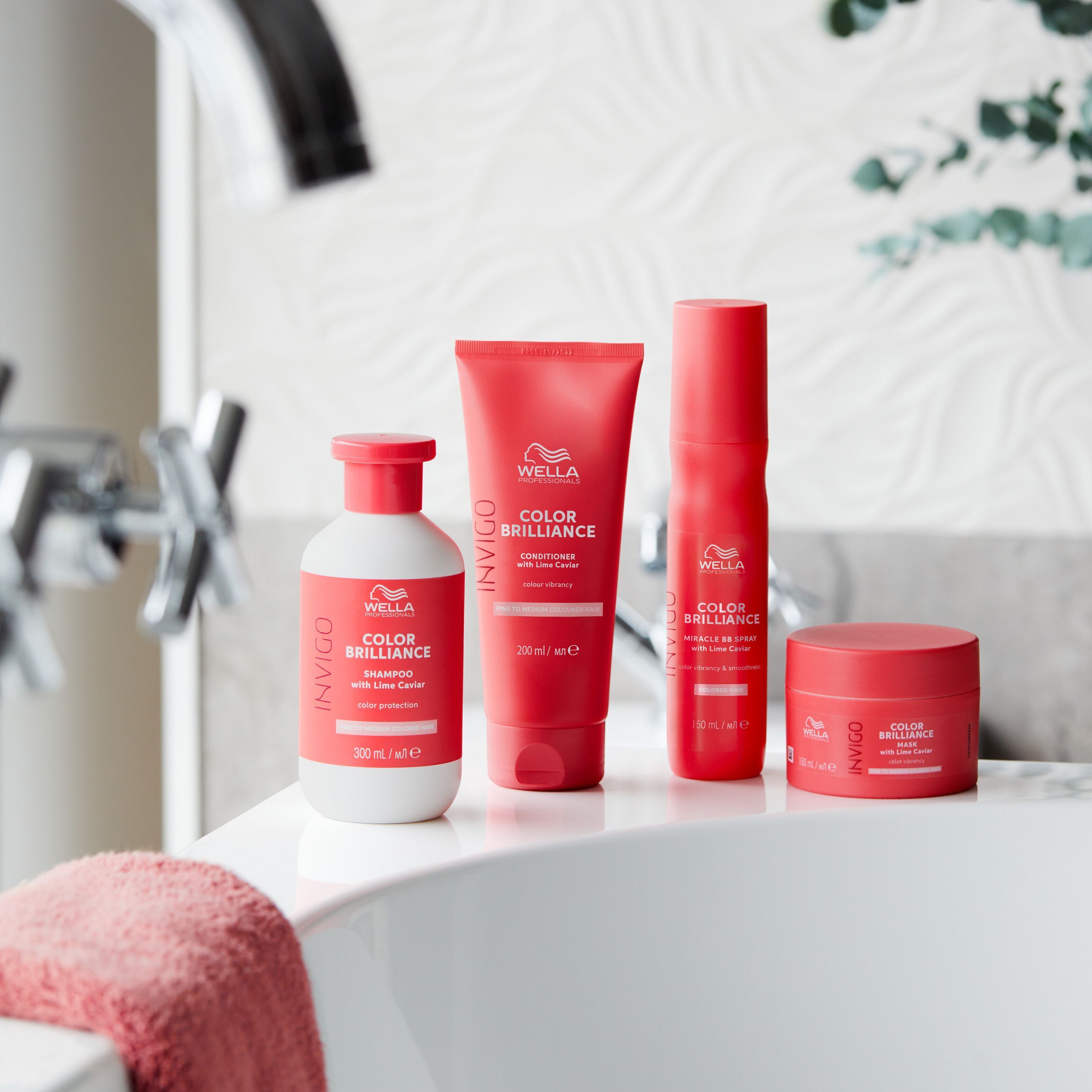 Produits capillaires Wella Invigo Color Brilliance dans des bouteilles et pots rouges sur une baignoire.