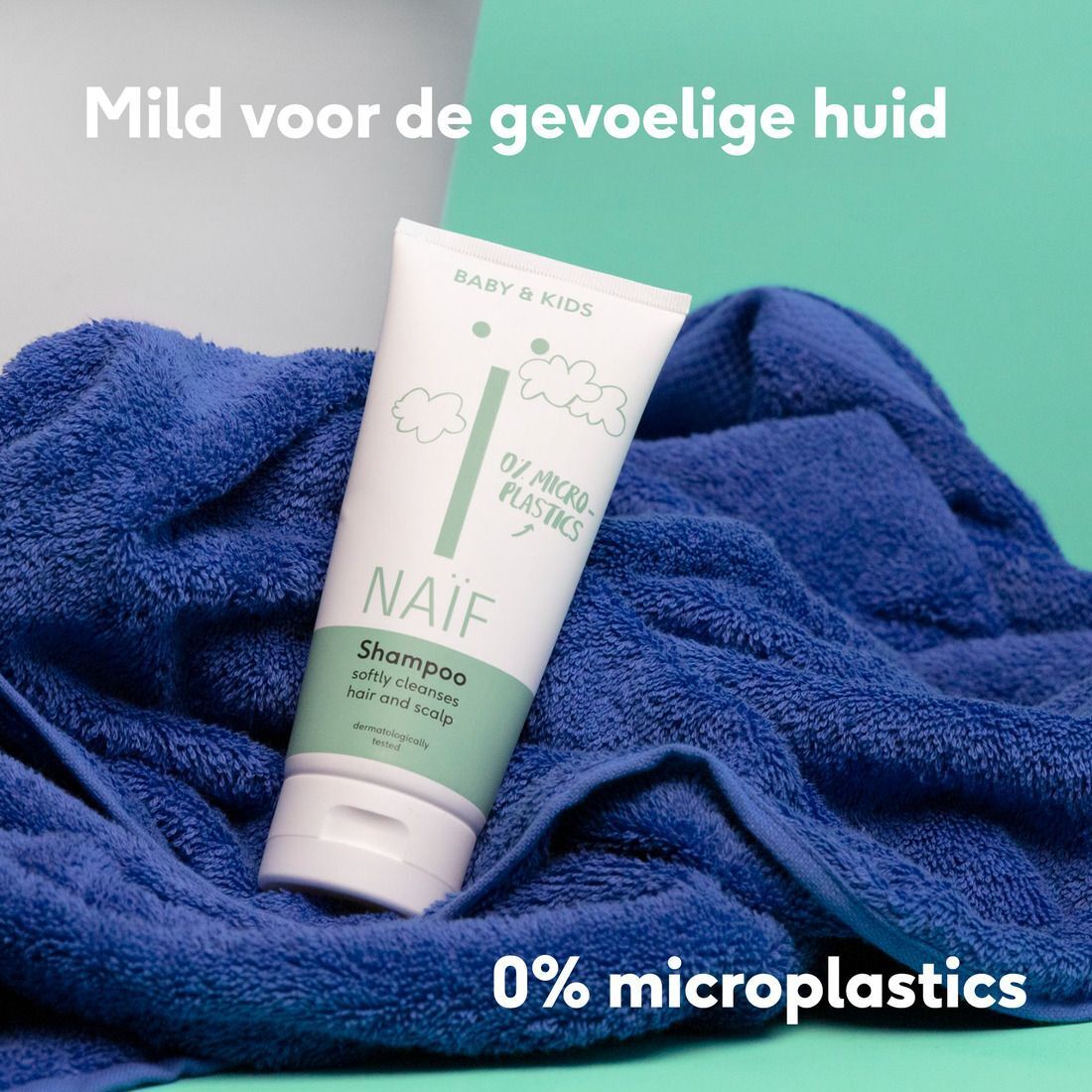 Naïf babyshampoo fles op een blauwe handdoek, 0% microplastics.