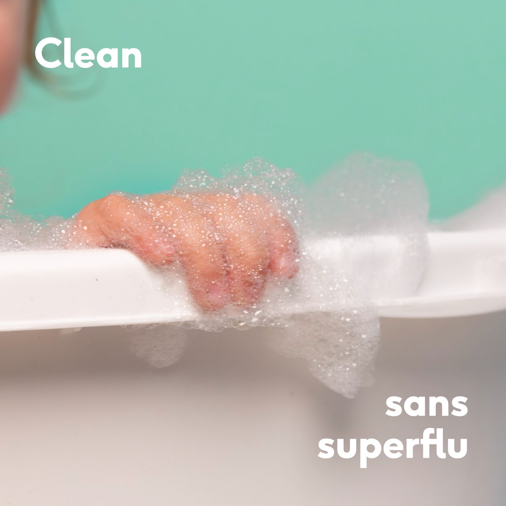 Gros plan d'une main de bébé dans la mousse. Texte : Propre, sans superflu.