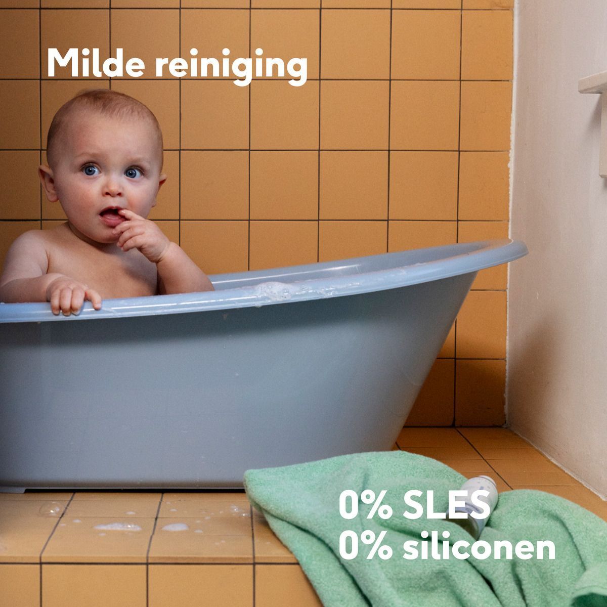 Een baby zit in een badkuip. Tekst: Dermatologisch getest, 0% SLES, 0% siliconen.