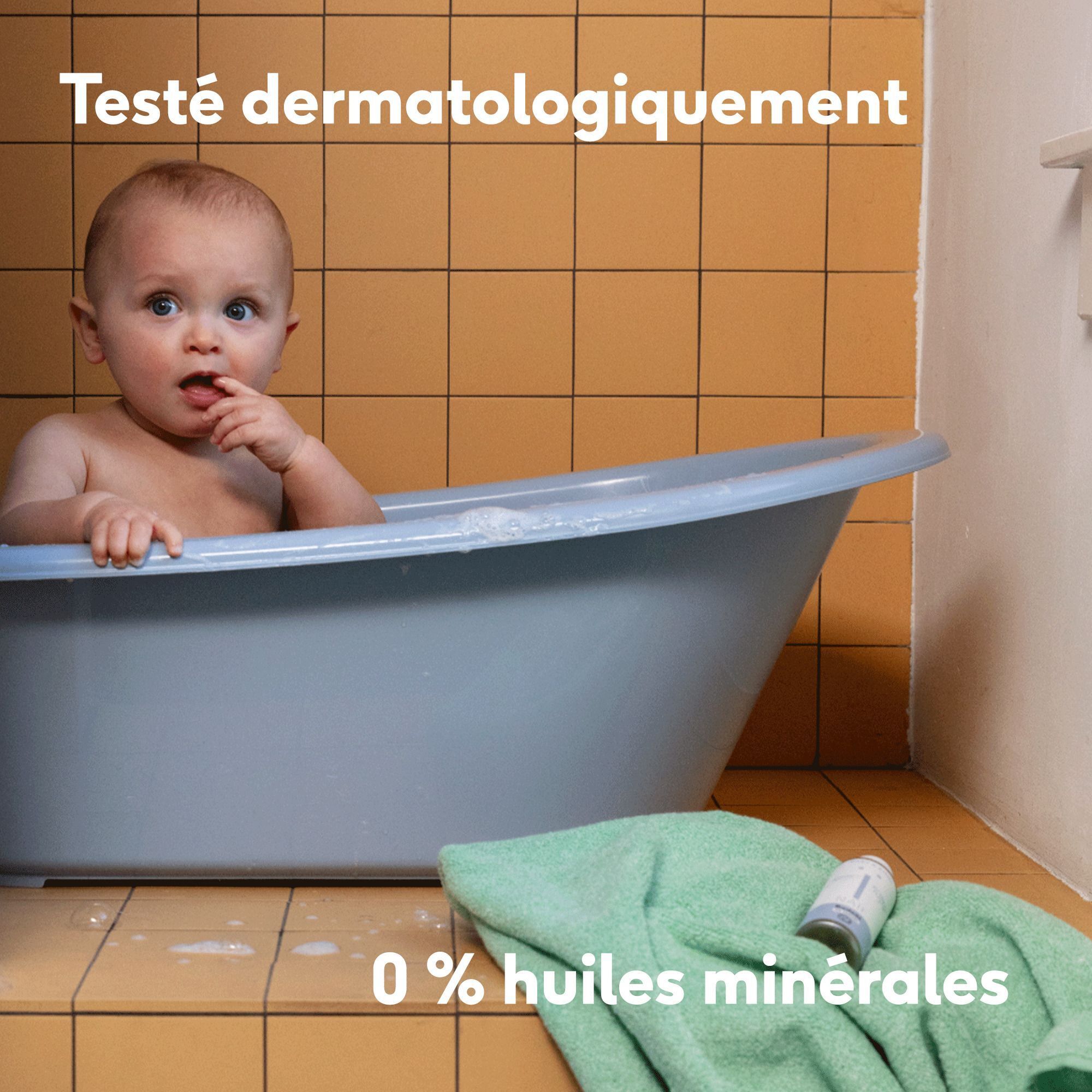Un bébé dans une baignoire. "Testé dermatologiquement" et "0% huiles minérales" sont indiqués.