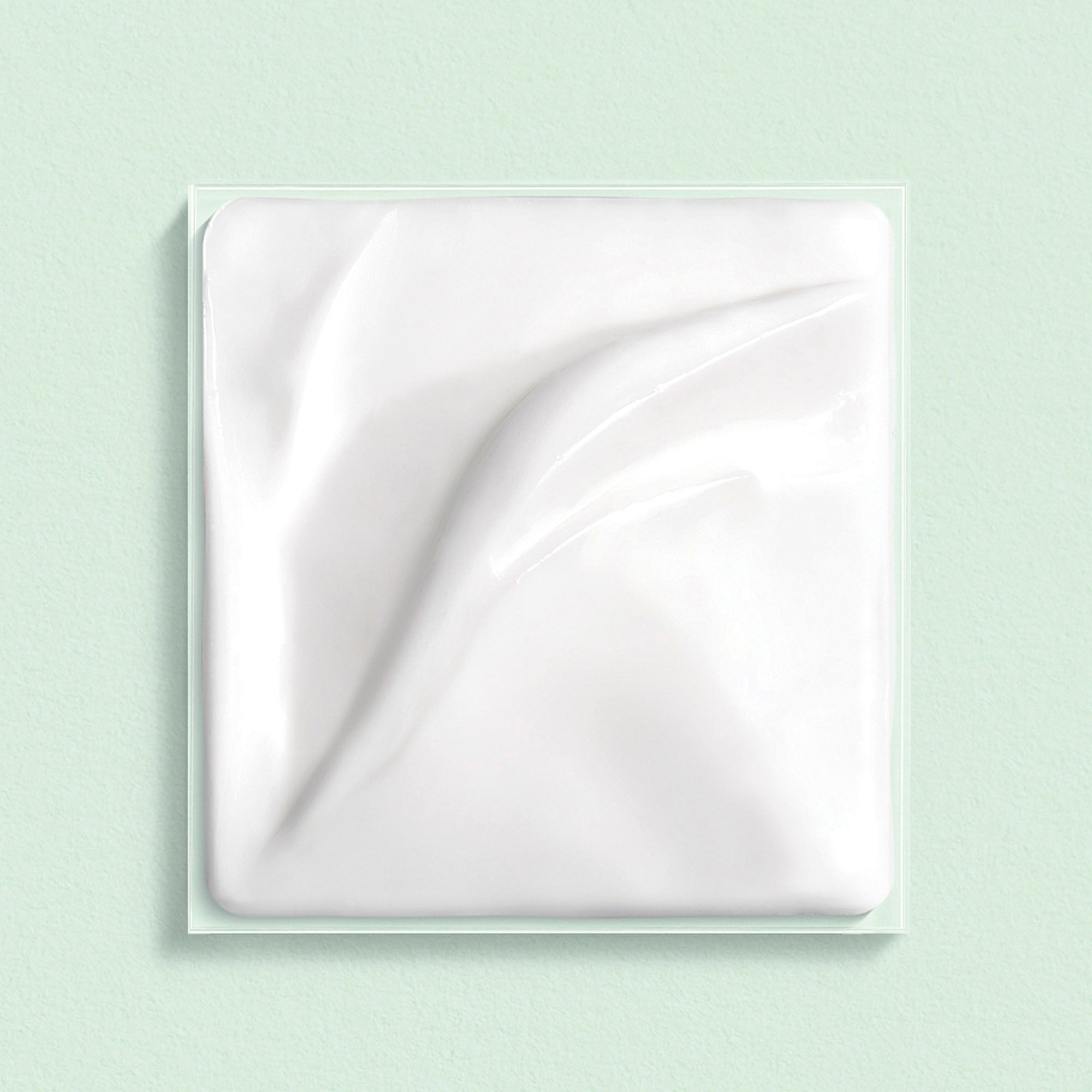Witte crème in een vierkante, transparante verpakking.