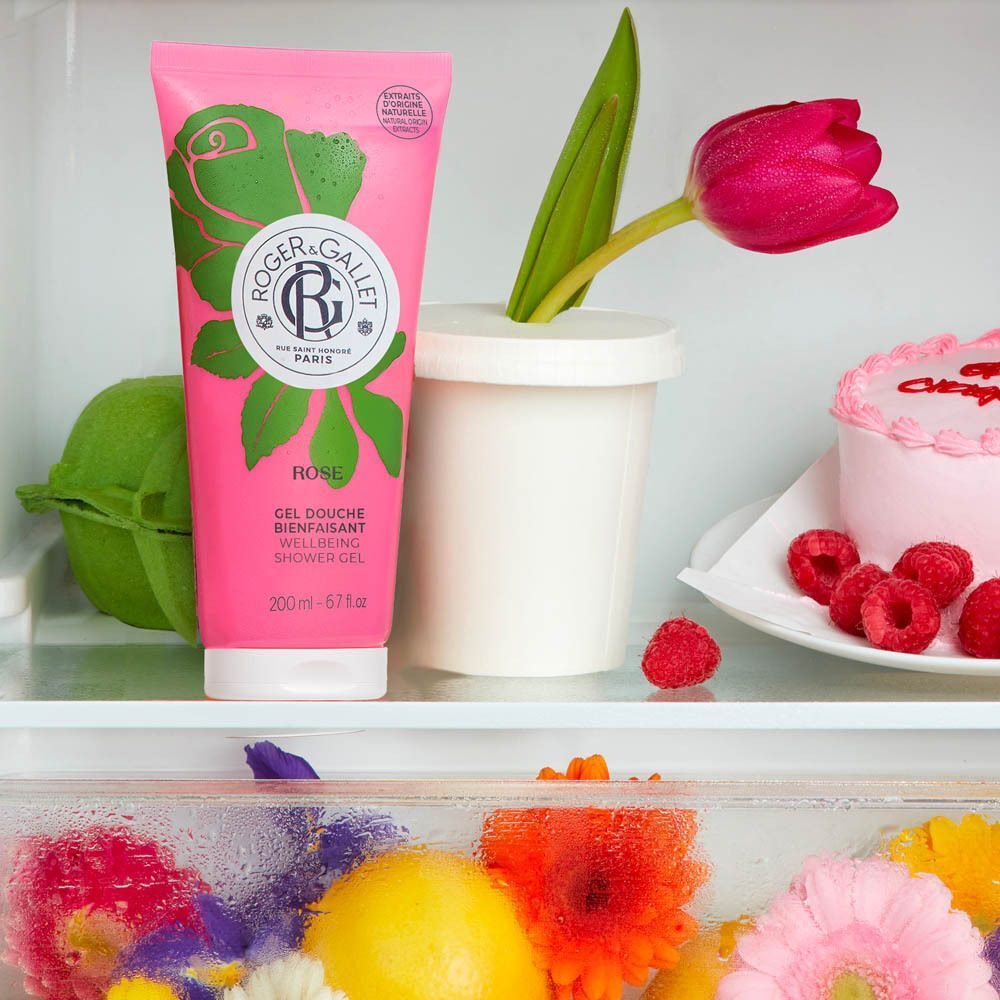 Tube de gel douche rose à côté d'une tulipe, de baies et d'un gâteau.