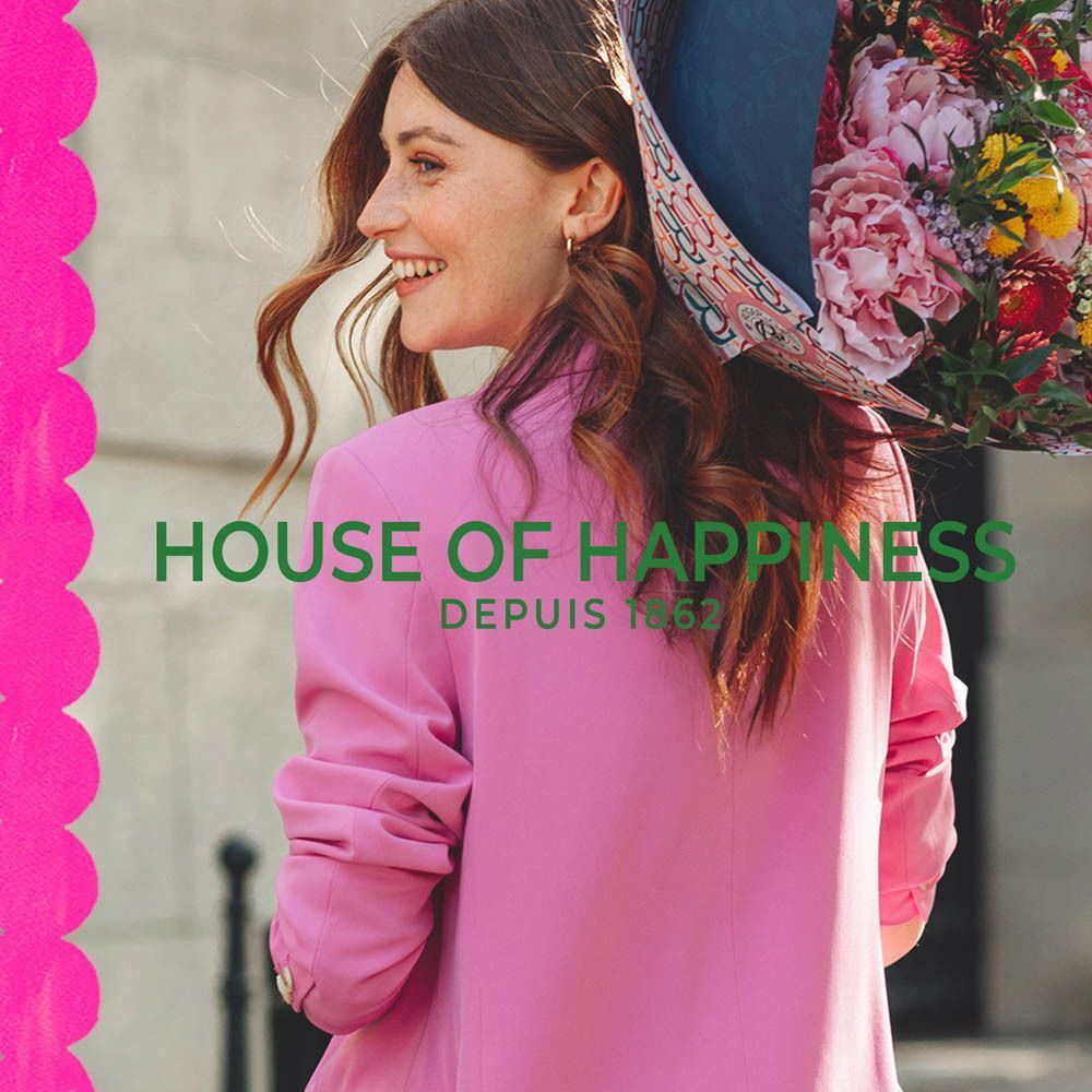 Femme en blazer rose avec bouquet de fleurs, texte : House of Happiness.