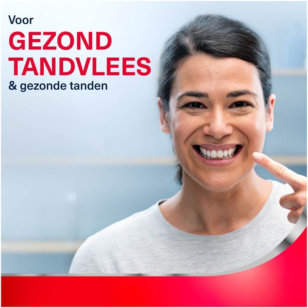 Vrouw wijst naar gezonde tanden en tandvlees. Tekst: Voor gezond tandvlees & gezonde tanden.
