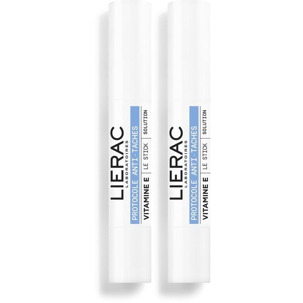 Deux sticks blancs avec étiquettes bleues, indiquant "Lierac Protocole Anti-Taches Vitamine E Le Stick Solution".