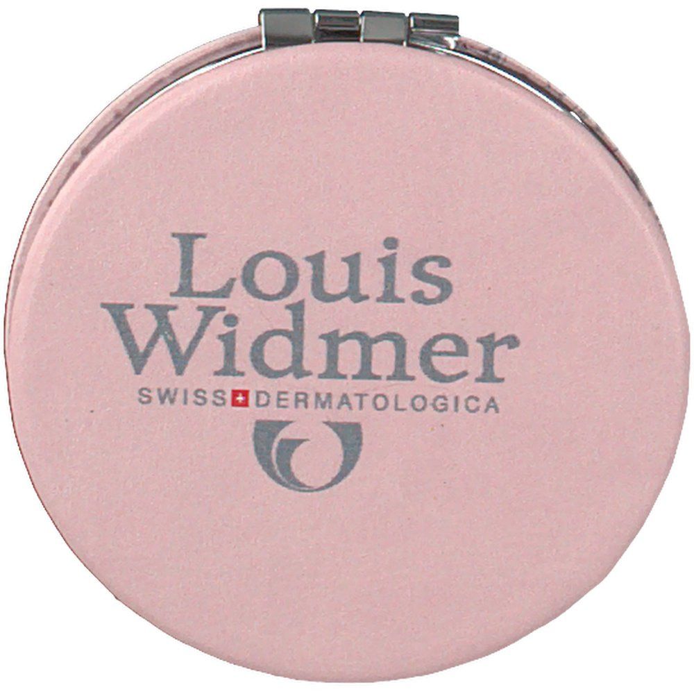 Miroir cosmétique rond rose. Inscription: Louis Widmer, Swiss Dermatologica. Charnière argentée.