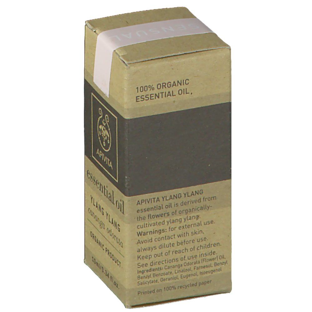 Kartonnen verpakking met productinformatie. Opschrift: 100% ORGANIC ESSENTIAL OIL. APIVITA YLANG YLANG, essential oil is derived from the flowers of organically cultivated ylang ylang.