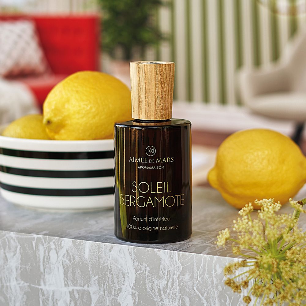 Flacon en verre brun avec bouchon en bois, à côté de citrons et d'un bol. Inscription: Soleil Bergamote. Marque: Aimée de Mars.