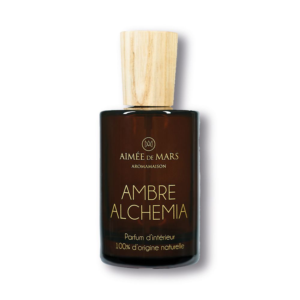 Bruine glazen fles met houten dop. Opschrift: AMBRE ALCHEMIA, Parfum d'intérieur, 100% d'origine naturelle.