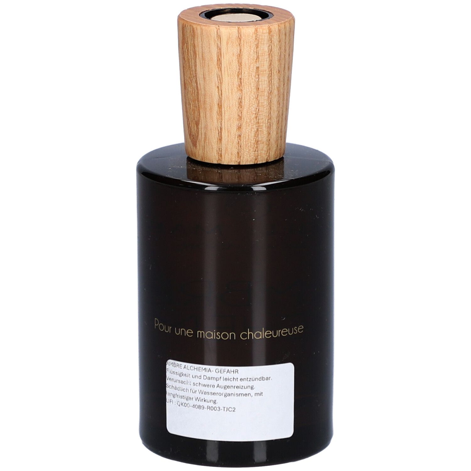 Bruine glazen fles met houten dop. Opschrift: AMBRE ALCHEMIA. Etiket met tekst. Merk: Aimée de Mars.