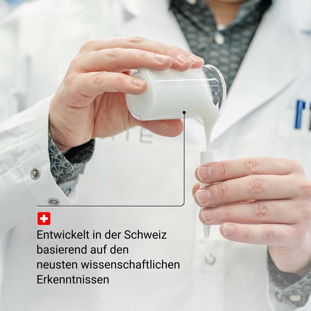 Persoon giet serum in een bakje. Laboratoriumomgeving. Tekst: Ontwikkeld in Zwitserland.