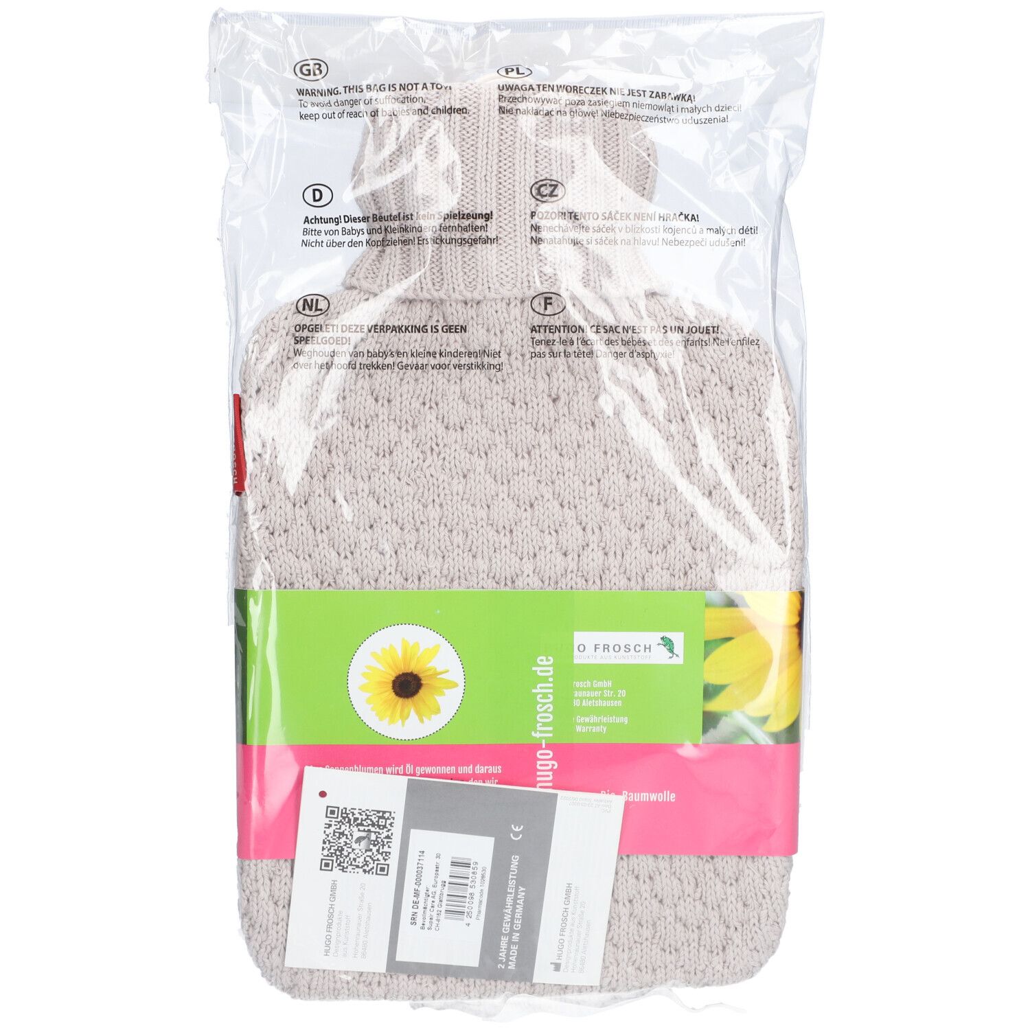 Warmwaterkruik in transparante verpakking. Beige gebreide hoes, groene band met logo en zonnebloem. Label met QR-code.