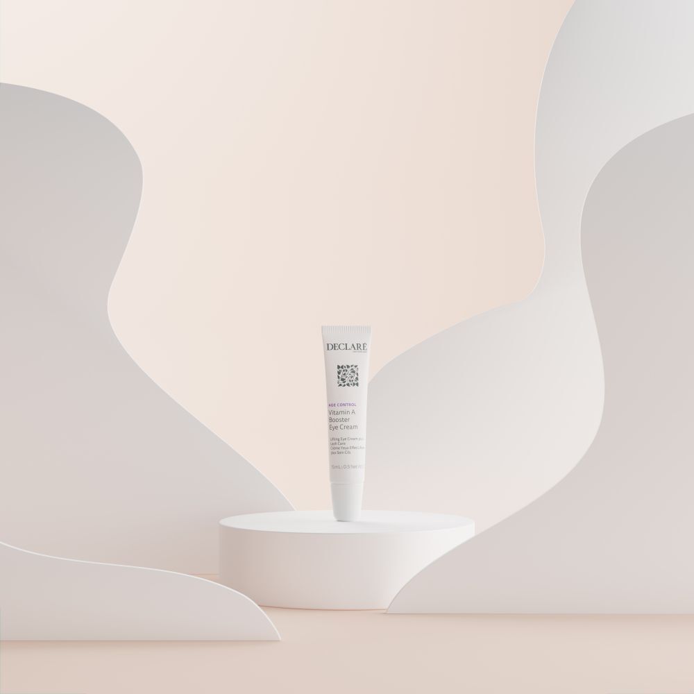 DECLARÉ Vitamin A Booster Eye Cream op sokkel. Achtergrond: abstracte witte en beige vormen.