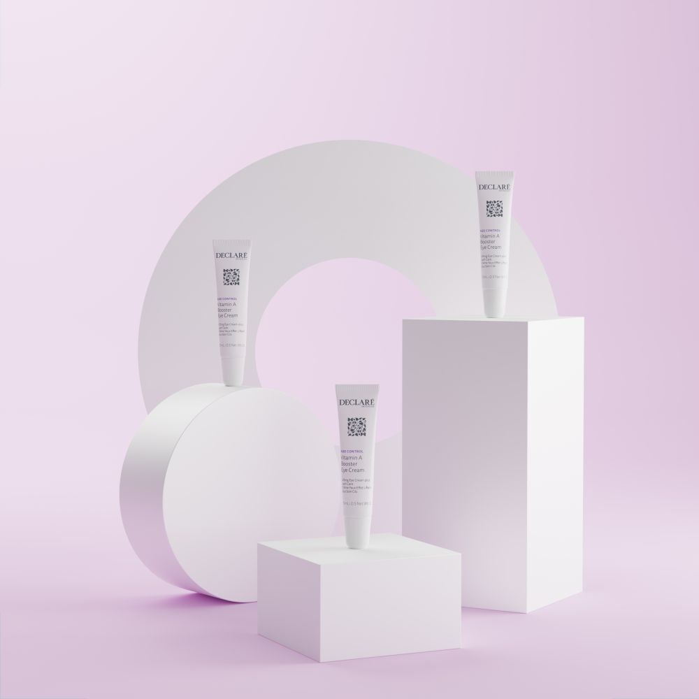 Drie tubes DECLARÉ Vitamin A Booster Eye Cream op sokkels. Achtergrond: geometrische vormen.