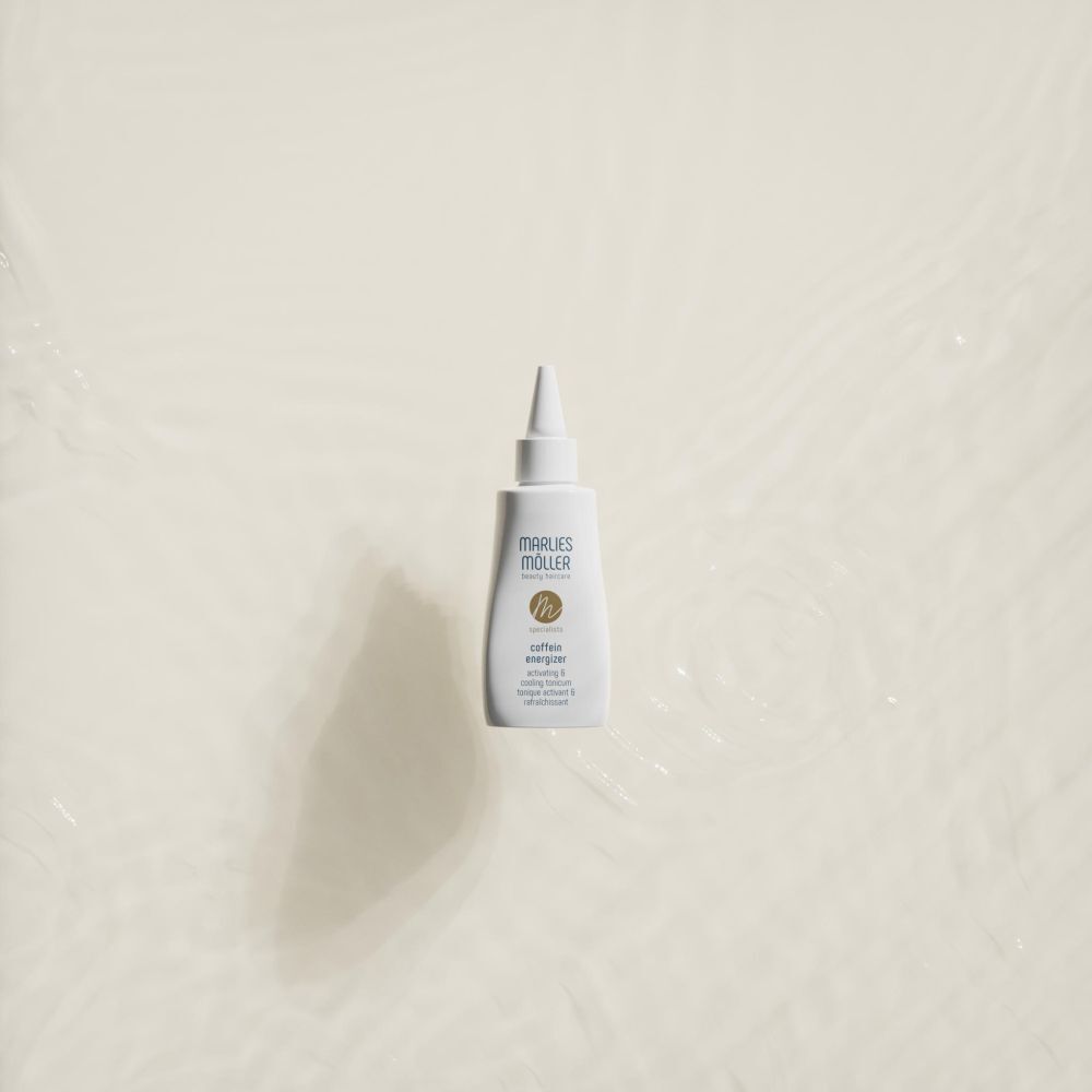 Witte fles met puntige applicator in water. Opschrift: Marlies Möller, Coffein Energizer.