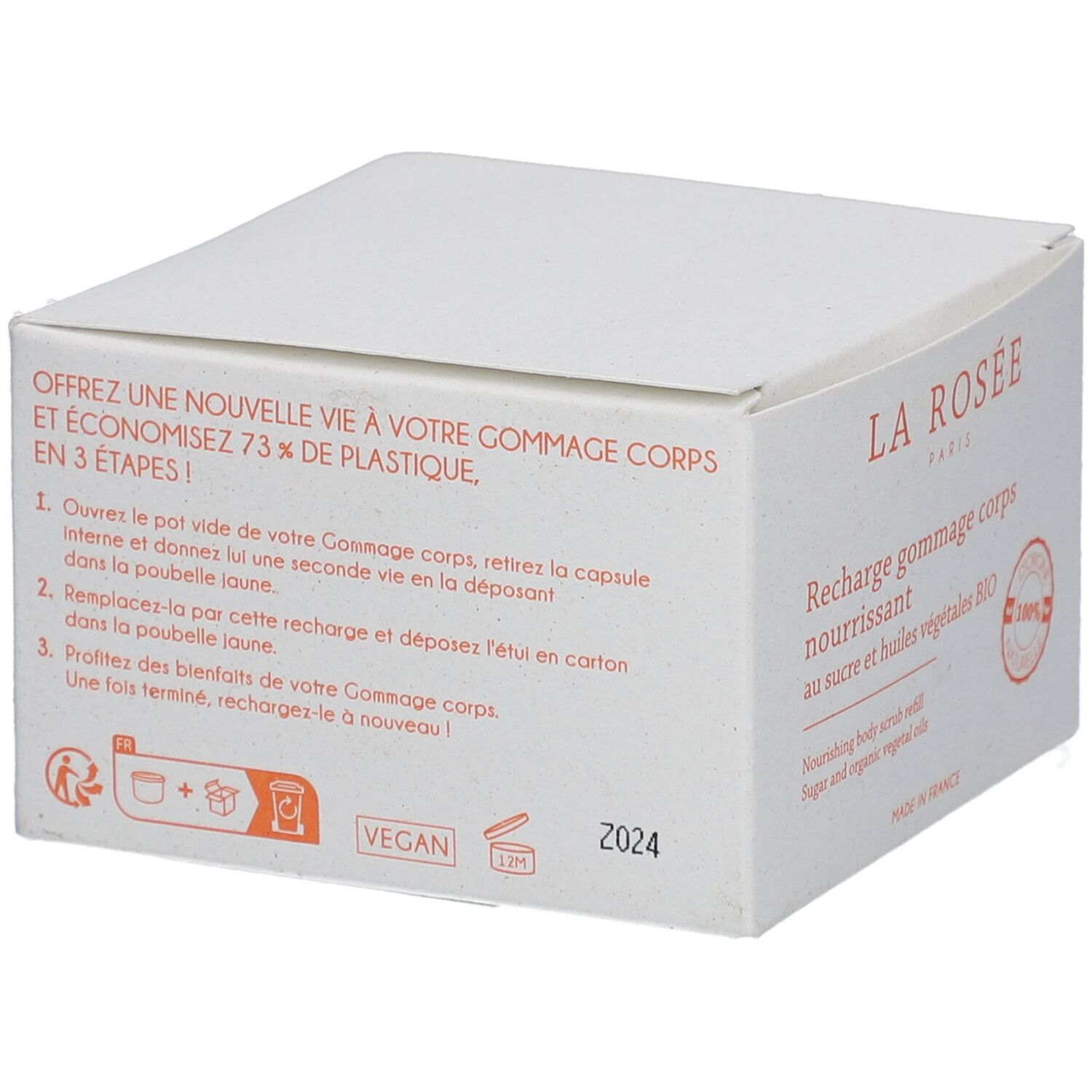 Boîte blanche avec texte. Inscription: LA ROSÉE, Recharge gommage corps nourrissant. Symbole vegan et consigne de recyclage.