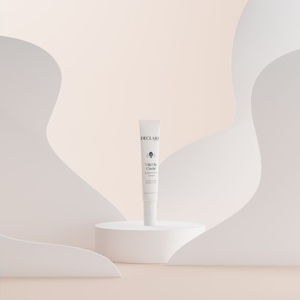 Witte tube 'Olu'Olu Caviar Supreme Eye Cream op sokkel. Achtergrond met witte vormen. DECLARÉ-logo zichtbaar.