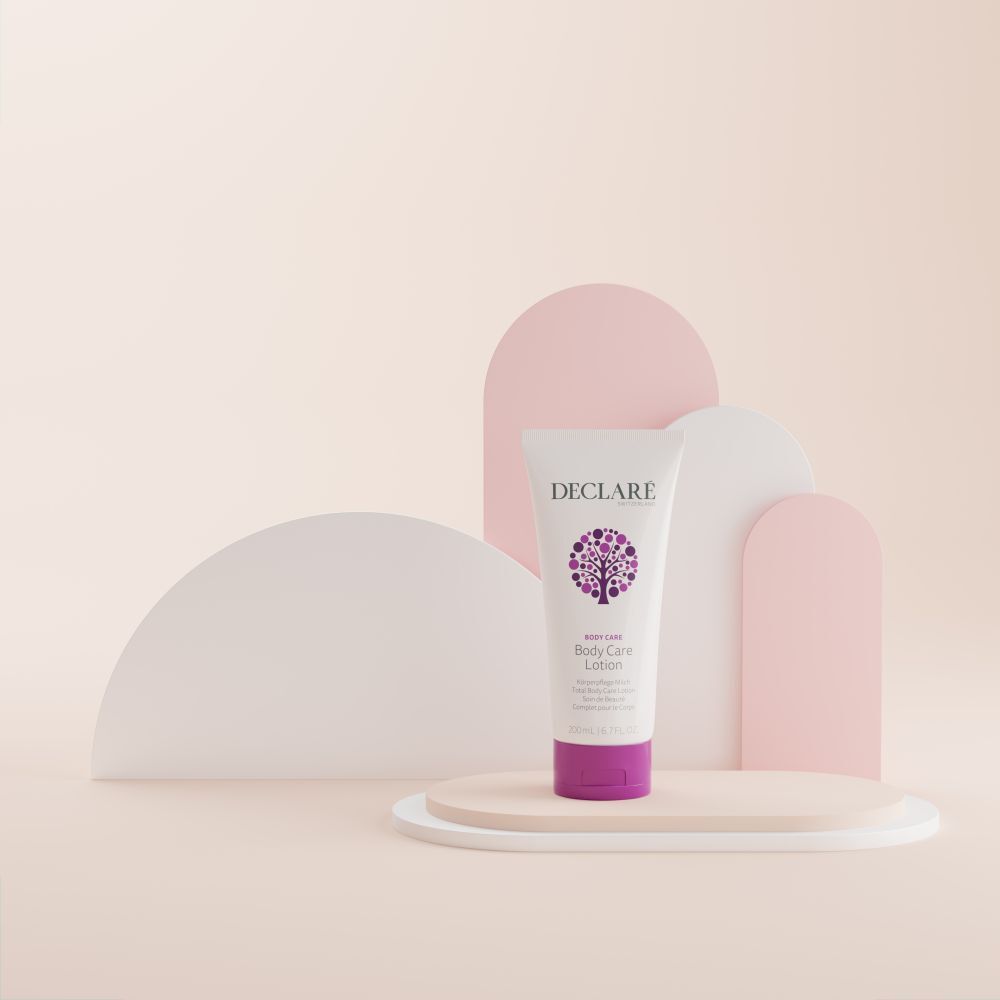 Tube blanc avec bouchon violet. Logo DECLARÉ et nom du produit Body Care Lotion. Sur socle. Fond.