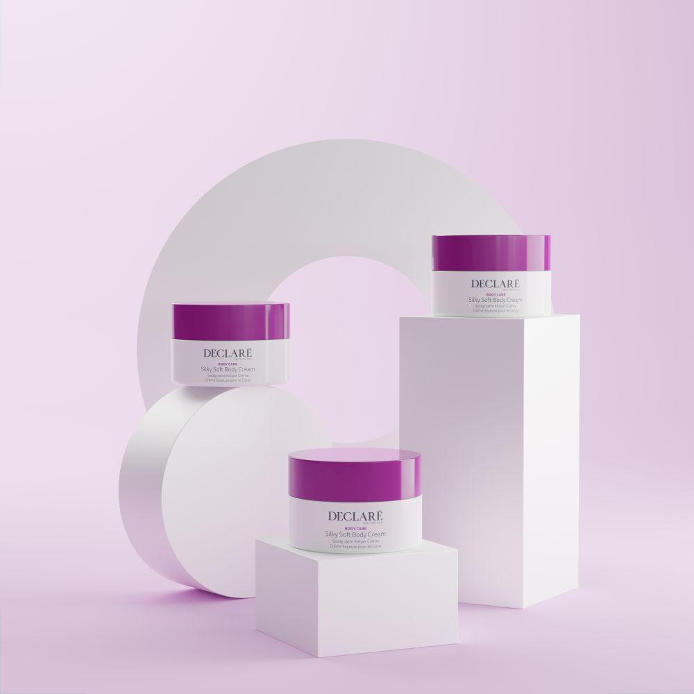 Meerdere witte potten met paarse deksels op sokkels. Decoratieve, geometrische vormen op de achtergrond. DECLARÉ-logo zichtbaar.