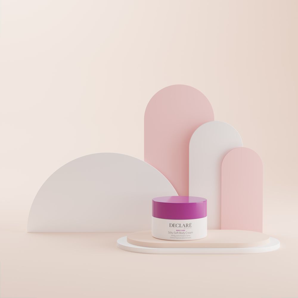 Witte pot met paarse deksel op sokkel. Decoratieve vormen in roze en wit op de achtergrond. DECLARÉ-logo zichtbaar.