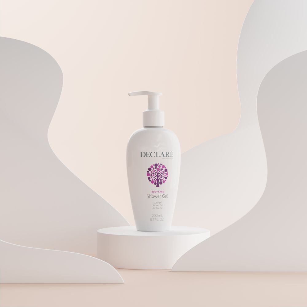 Witte DECLARÉ-fles met pomp op sokkel. Achtergrond met witte, gebogen vormen. Productnaam: Shower Gel.