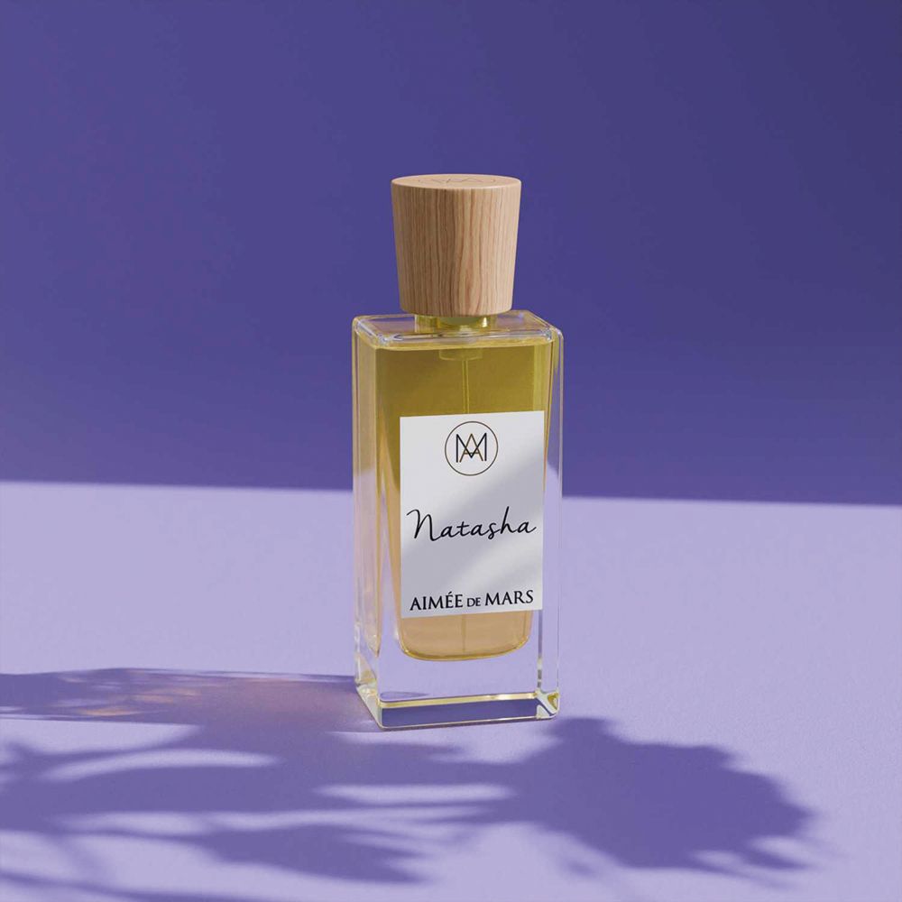 Flacon Aimée de Mars Natasha Eau de Parfum sur fond violet. Bouchon bois, étiquette blanche.