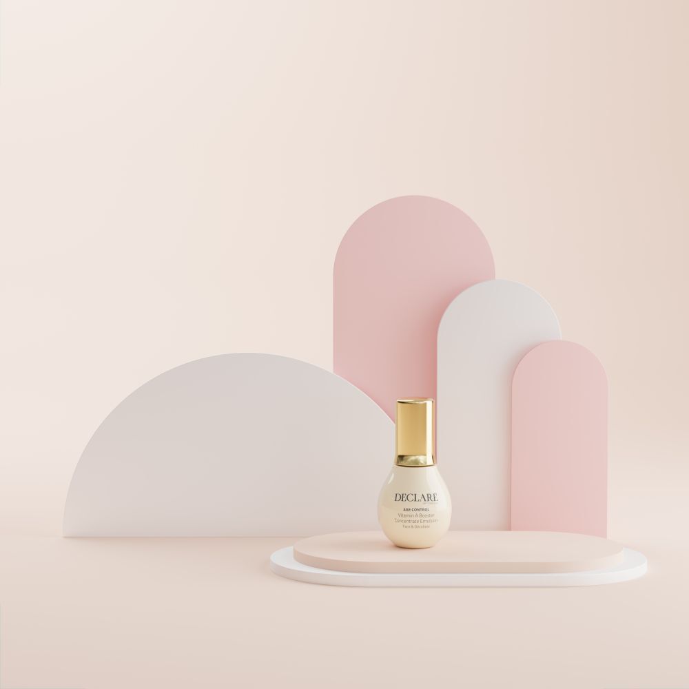 Flacon sur socle. Fond : formes roses, blanches et roses. DECLARÉ Age Control Vitamin A Booster.