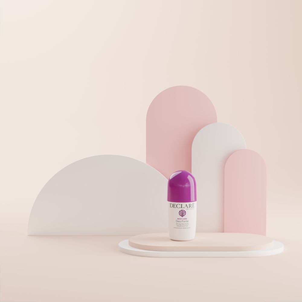 Roll-on Deo Forte sur socle. Fond : formes abstraites roses et blanches. Bouchon violet visible.