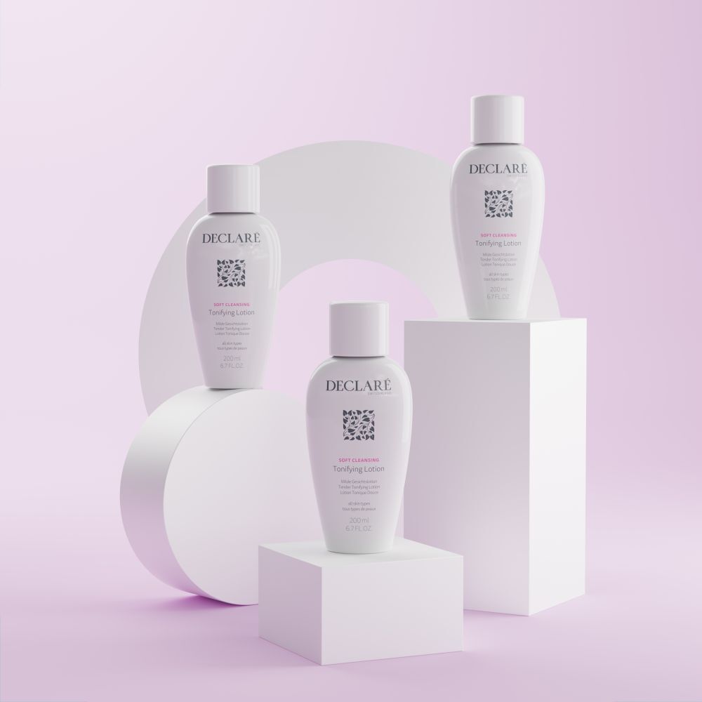 Drie witte flessen DECLARÉ Toning Lotion op sokkels. Opschrift: Soft Cleansing, Toning Lotion. Achtergrond: roze.