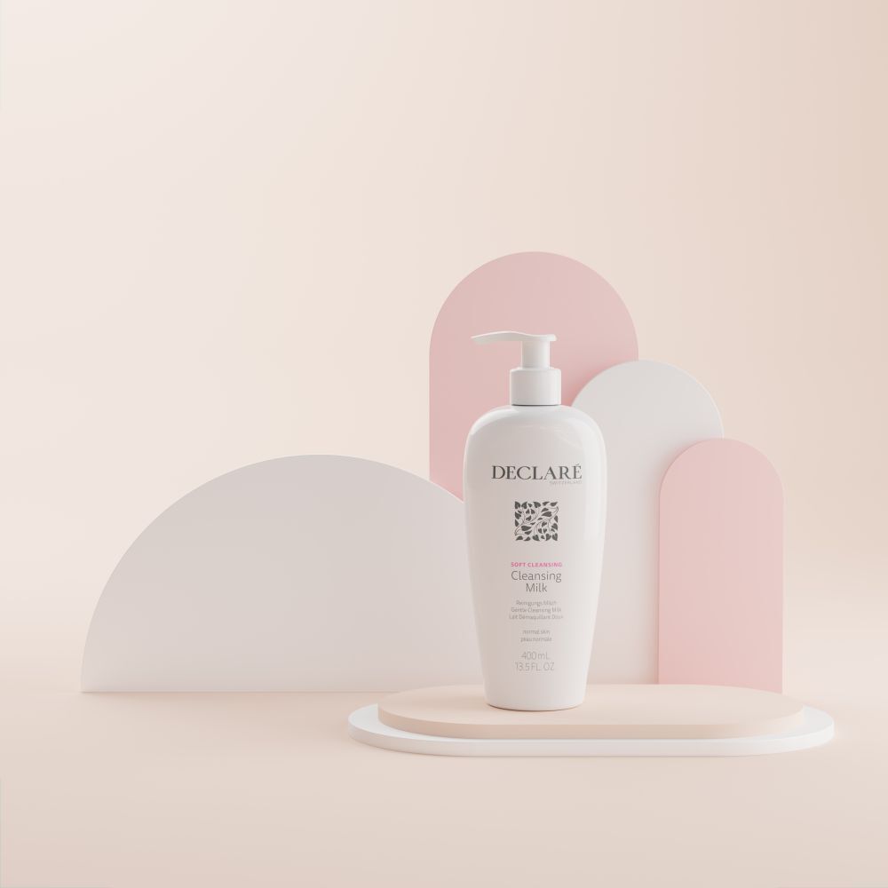 Witte fles met pomp op sokkel. DECLARÉ Cleansing Milk, 400ml. Achtergrond met vormen.