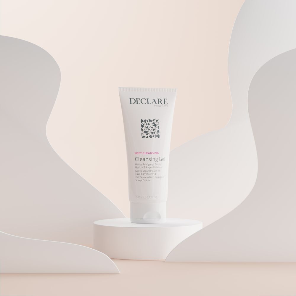 Witte tube DECLARÉ Cleansing Gel op voetstuk. Achtergrond: abstracte vormen in pasteltinten.