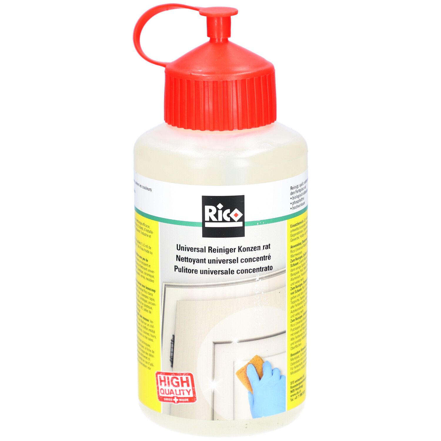 Fles met rode dop. Opschrift: Rico, Universalreiniger concentraat. Gele en witte etiketten. Spons en deur op de achtergrond.