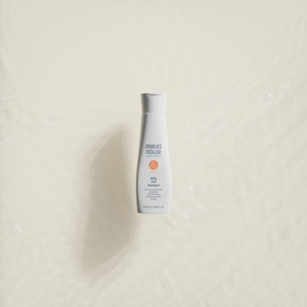 Flacon blanc Marlies Möller Daily Rich Shampoo sur fond clair. Logo orange. Flacon avec bouchon blanc.