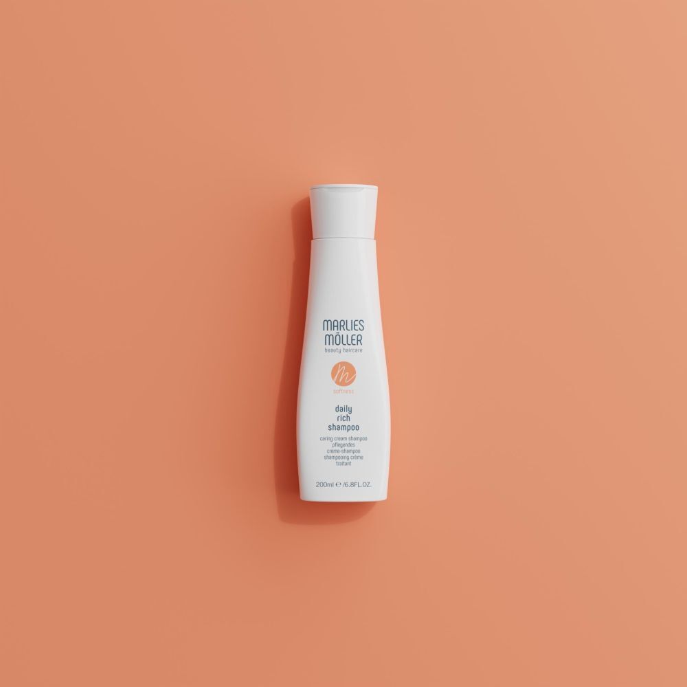 Flacon blanc Marlies Möller Daily Rich Shampoo sur fond orange. Logo orange. Flacon avec bouchon blanc.