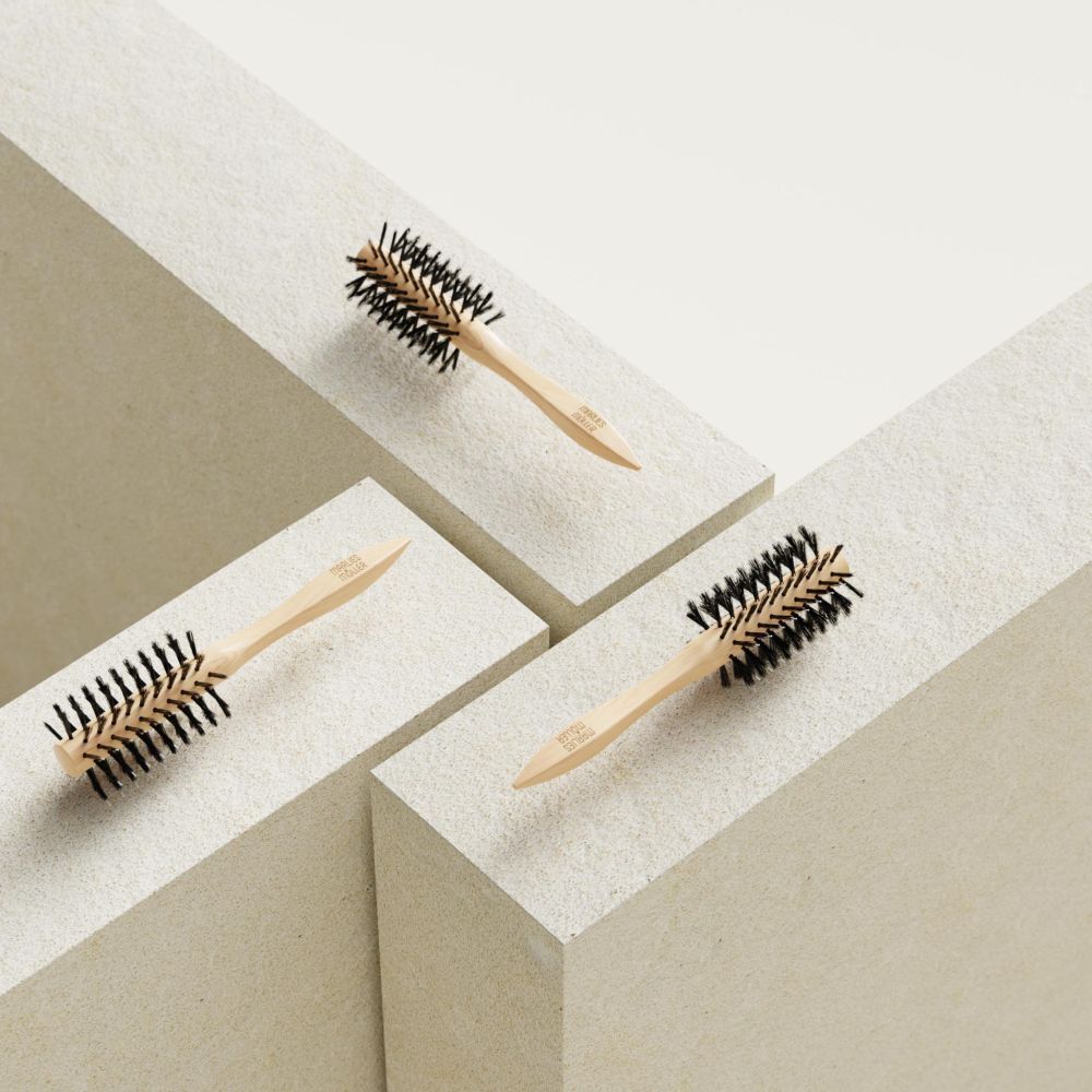 Drie ronde haarborstels op witte blokken. Houten handvat, zwarte borstelharen.