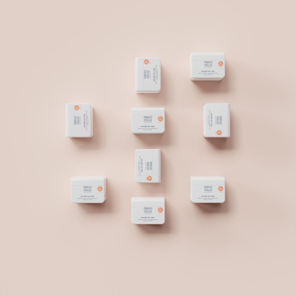 Plusieurs contenants blancs Marlies Möller Overnight Hair Mask, sur fond rose. Vue de dessus.