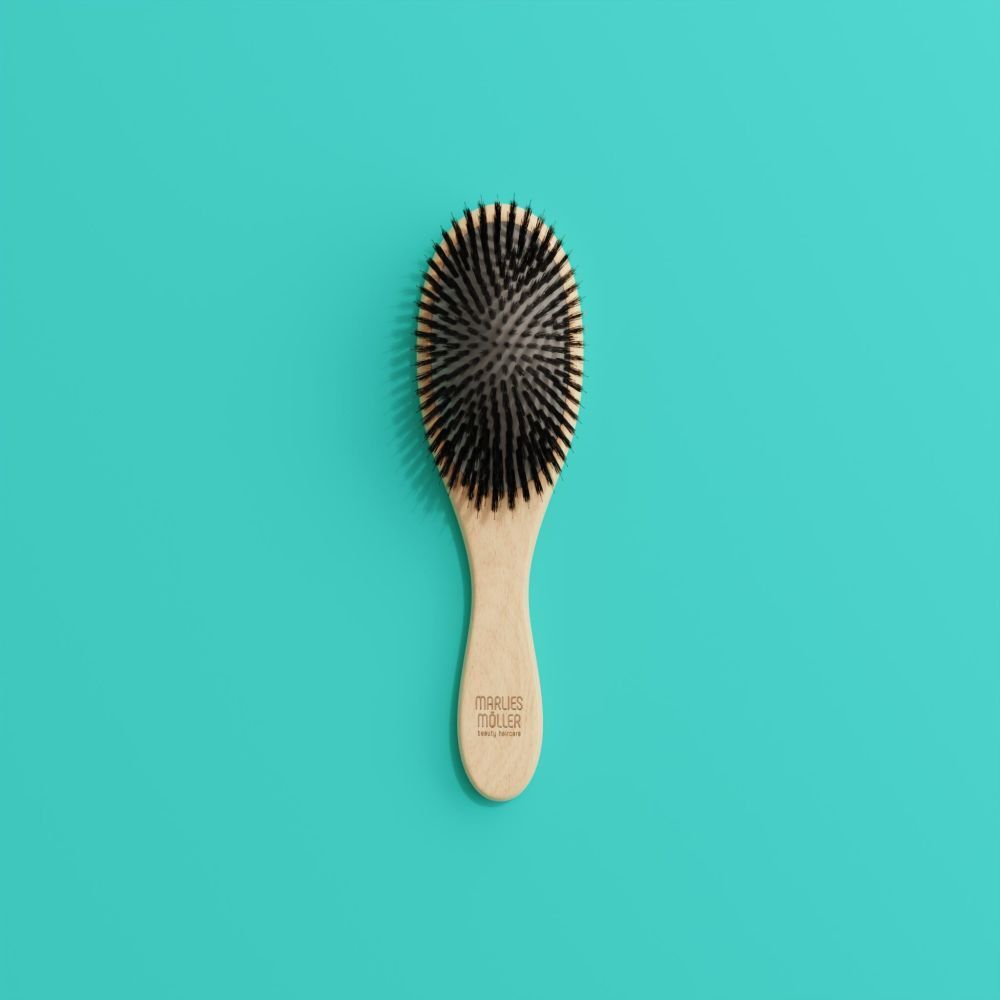 Brosse à cheveux ovale, manche en bois, soies noires, sur fond turquoise.
