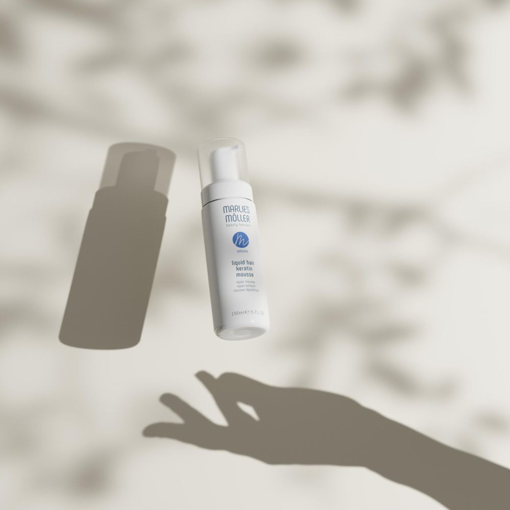 Witte fles met spuitkop. Opschrift: Marlies Möller, beauty haircare, Volume, Liquid Hair Keratin Mousse. Met schaduwen.