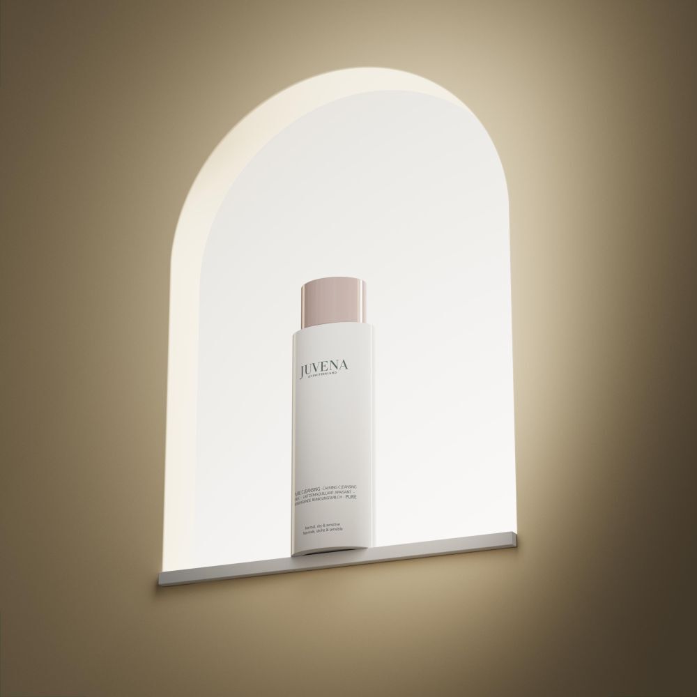 Flacon blanc avec bouchon rose. Inscription: Juvena. Produit dans une niche éclairée.