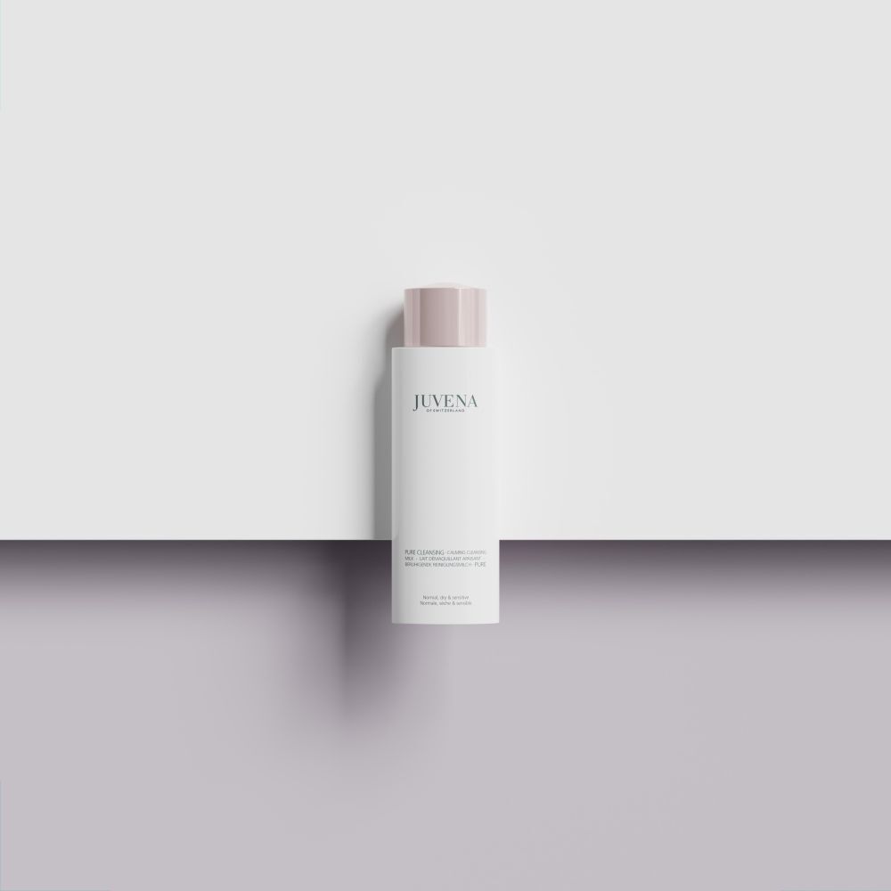 Flacon blanc avec bouchon rose. Inscription: Juvena. Le produit est posé sur une surface blanche.