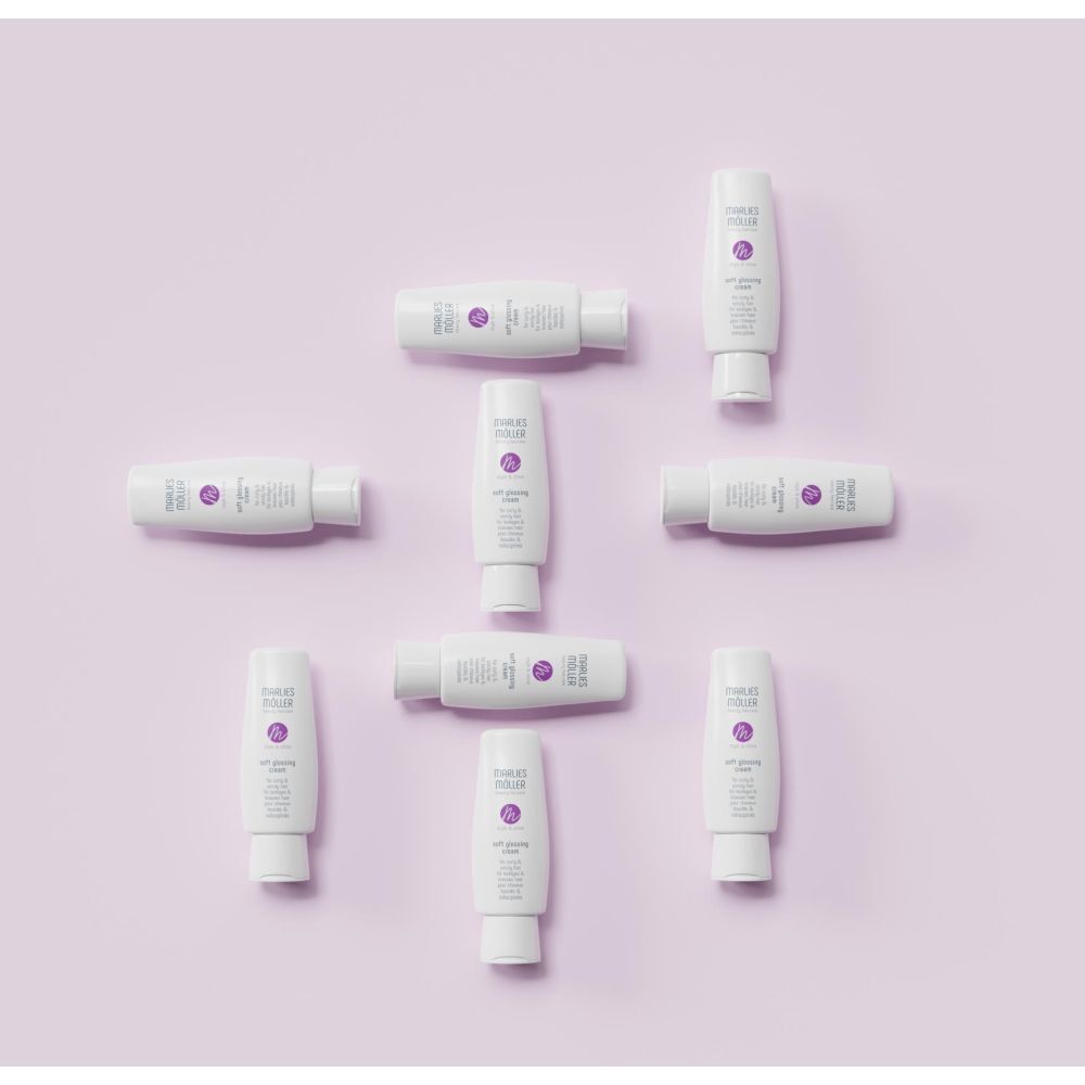 Opstelling van witte tubes, Marlies Möller Soft Glossing Cream, op paarse achtergrond. Negen tubes.