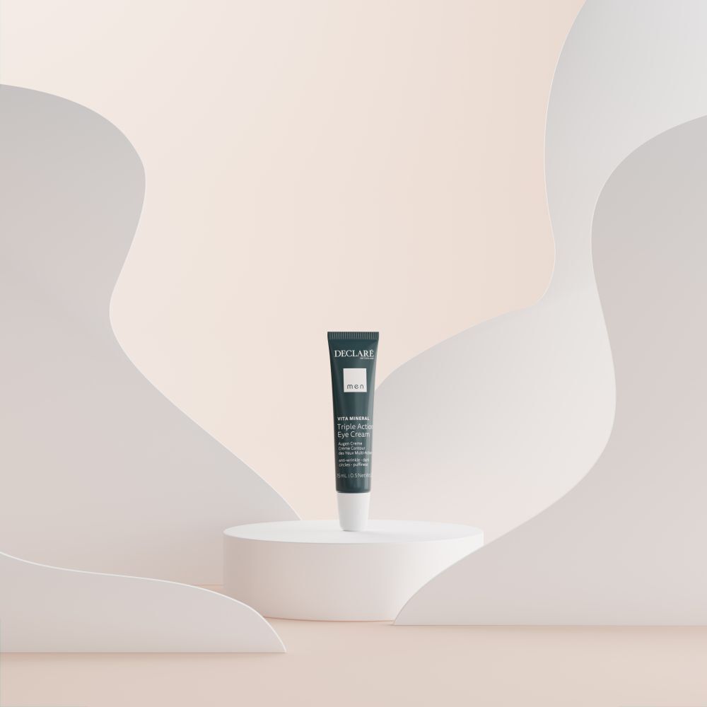Productpresentatie. Blauwe DECLARÉ oogcrèmetube op wit voetstuk. Achtergrond met witte vormen.