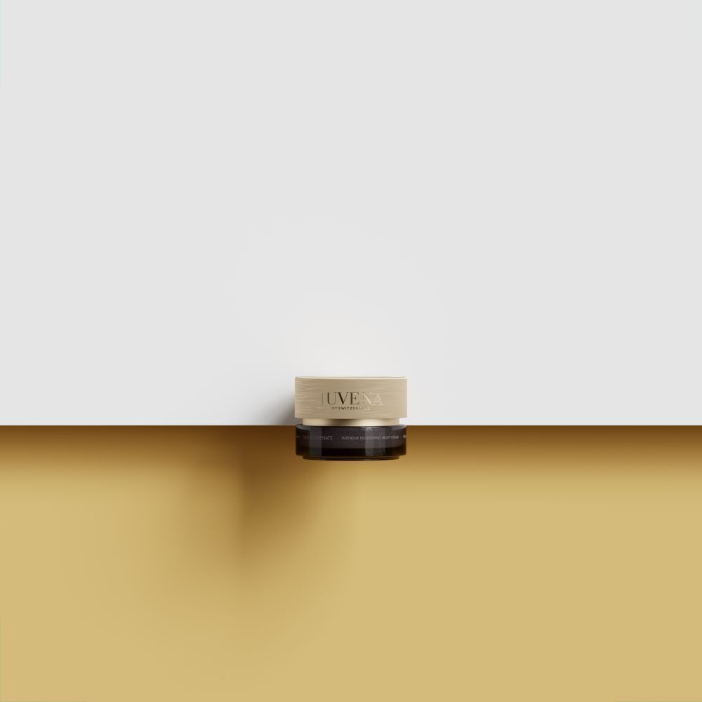 Pot de crème avec couvercle doré. Inscription : JUVENA. Placé sur une surface dorée. Fond : jaune et blanc.