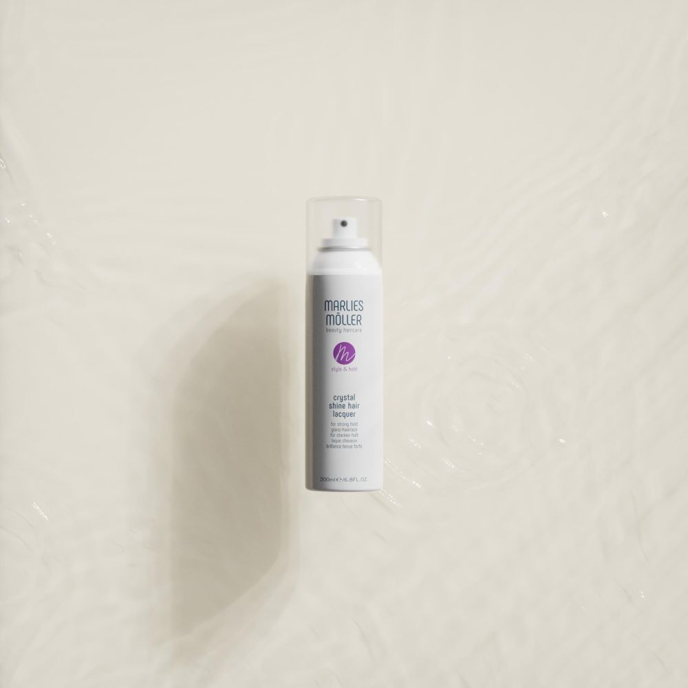 Wit haarspray van Marlies Möller in water. Opschrift: Crystal Shine Hair Lacquer.